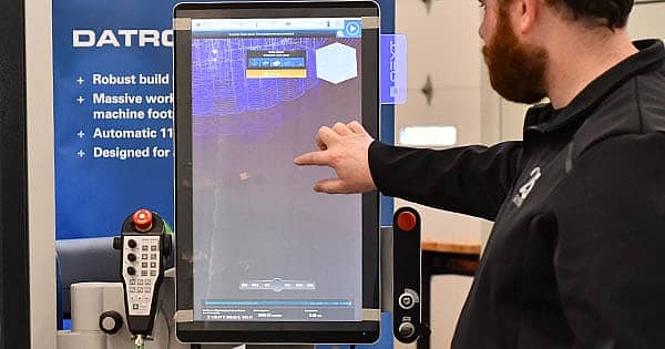 machinist demonstrating computer numerical control programming hacks on a touch screen